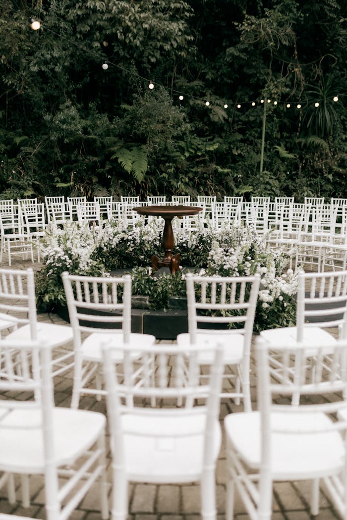 Beautiful outdoor wedding setup with circular white chairs and floral center.